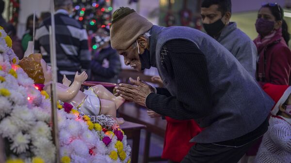 An elderly Indian Christian man touches the feet of the statue of baby Jesus after attending a Christmas mass at Saint Mary's church in Noida, a suburb of New Delhi, India, Saturday, Dec. 25, 2021. - Sputnik भारत