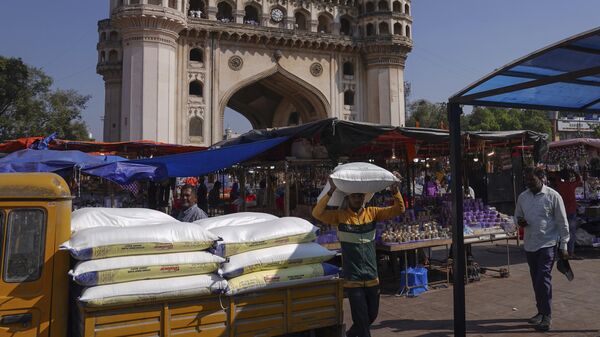 A worker carries a sack of refined wheat flour towards a hotel in front of the landmark Charminar monument in Hyderabad, India, Thursday, Nov. 17, 2022. - Sputnik भारत
