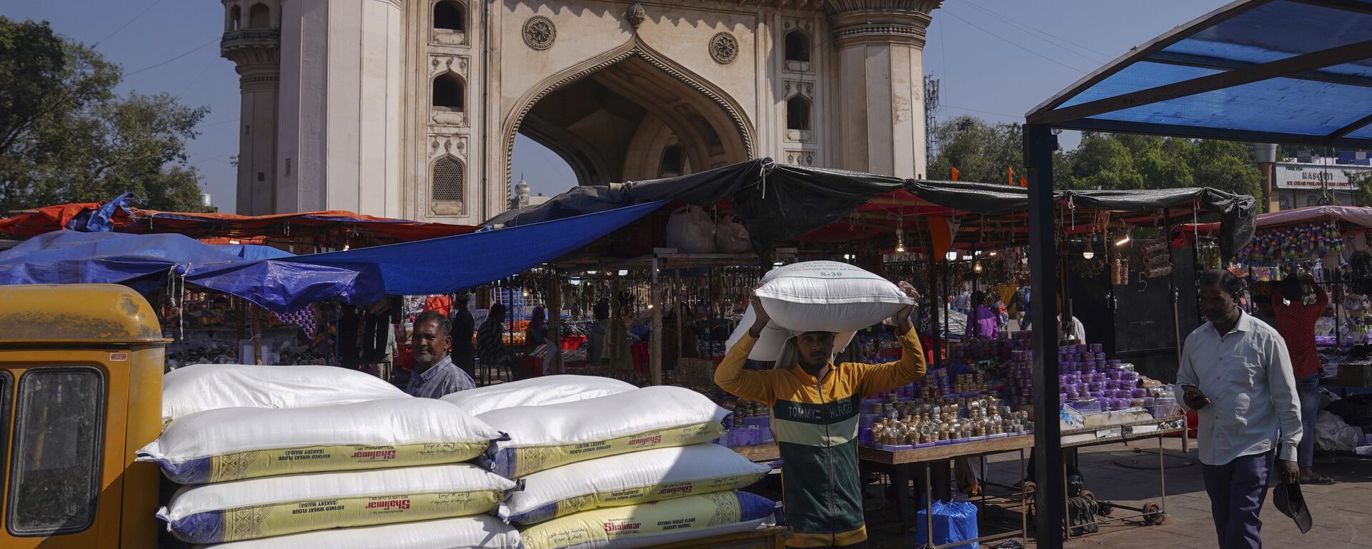 A worker carries a sack of refined wheat flour towards a hotel in front of the landmark Charminar monument in Hyderabad, India, Thursday, Nov. 17, 2022. - Sputnik India, 1920, 15.12.2022