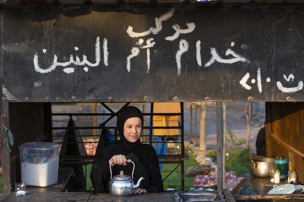 A girl offers tea to passing Iraqi Shiite Muslim pilgrims marching from the southern port city of Basra to the holy city of Karbala, ahead of the Arbaeen religious festival, on September 10, 2021. - Sputnik India
