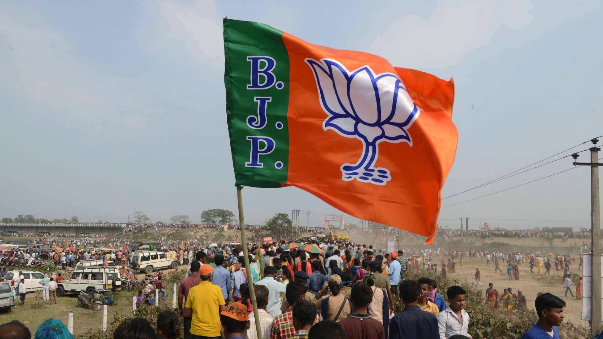 Indian supporters of the Bharatiya Janata Party (BJP) carry a party flag on their way to attend a campaign rally while wearing masks of Indian Prime Minister Narendra Modi ahead of the national elections in Siliguri on April 3, 2019 - Sputnik India, 1920, 02.03.2023