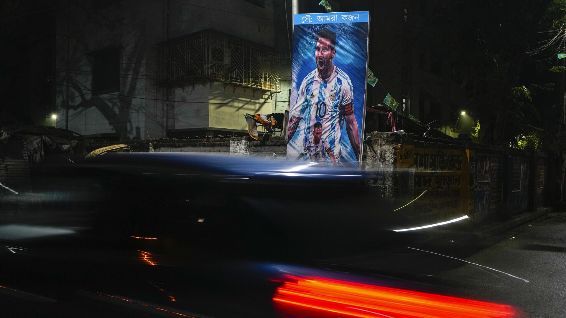 A car passes a poster of Argentina's Leonel Messi, erected by the Indian fans of Argentina during the World Cup semi final soccer match between Argentina and Croatia in Qatar, Wednesday, Dec. 14, 2022. - Sputnik India, 1920, 19.12.2022