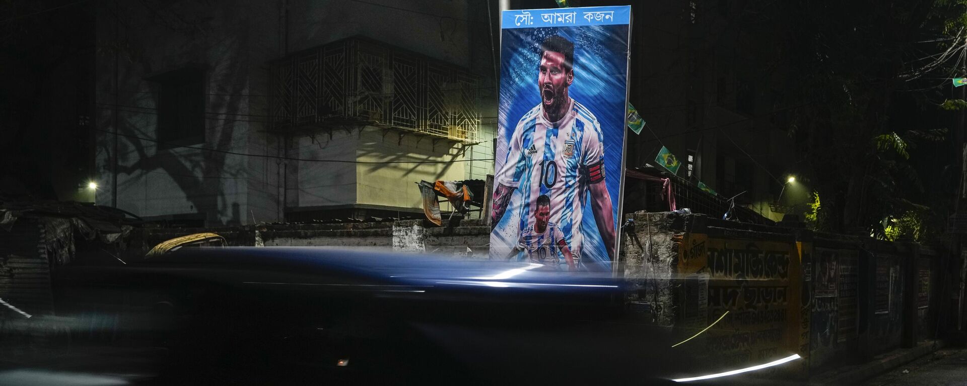 A car passes a poster of Argentina's Leonel Messi, erected by the Indian fans of Argentina during the World Cup semi final soccer match between Argentina and Croatia in Qatar, Wednesday, Dec. 14, 2022. - Sputnik India, 1920, 19.12.2022