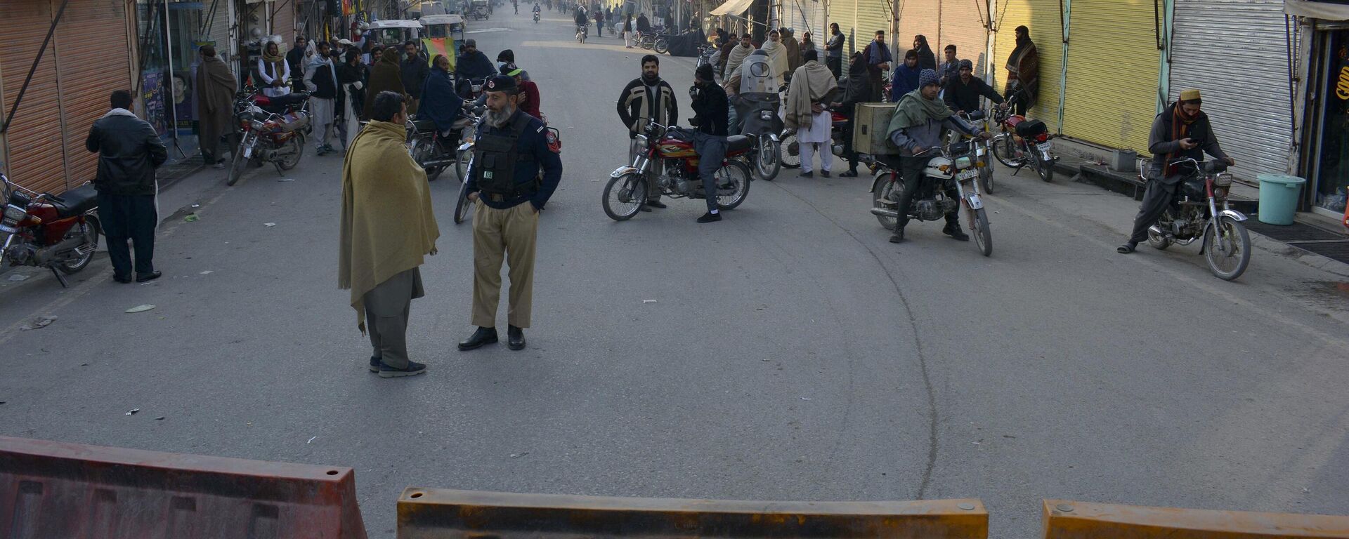 Security officials stand guard on a blocked road leading to a counter-terrorism center where several Pakistani Taliban detainees have taken police officers and others hostage inside the compound, in Bannu, a district in the Pakistan's Khyber Pakhtunkhwa province, Monday, Dec. 19, 2022. - Sputnik India, 1920, 20.12.2022