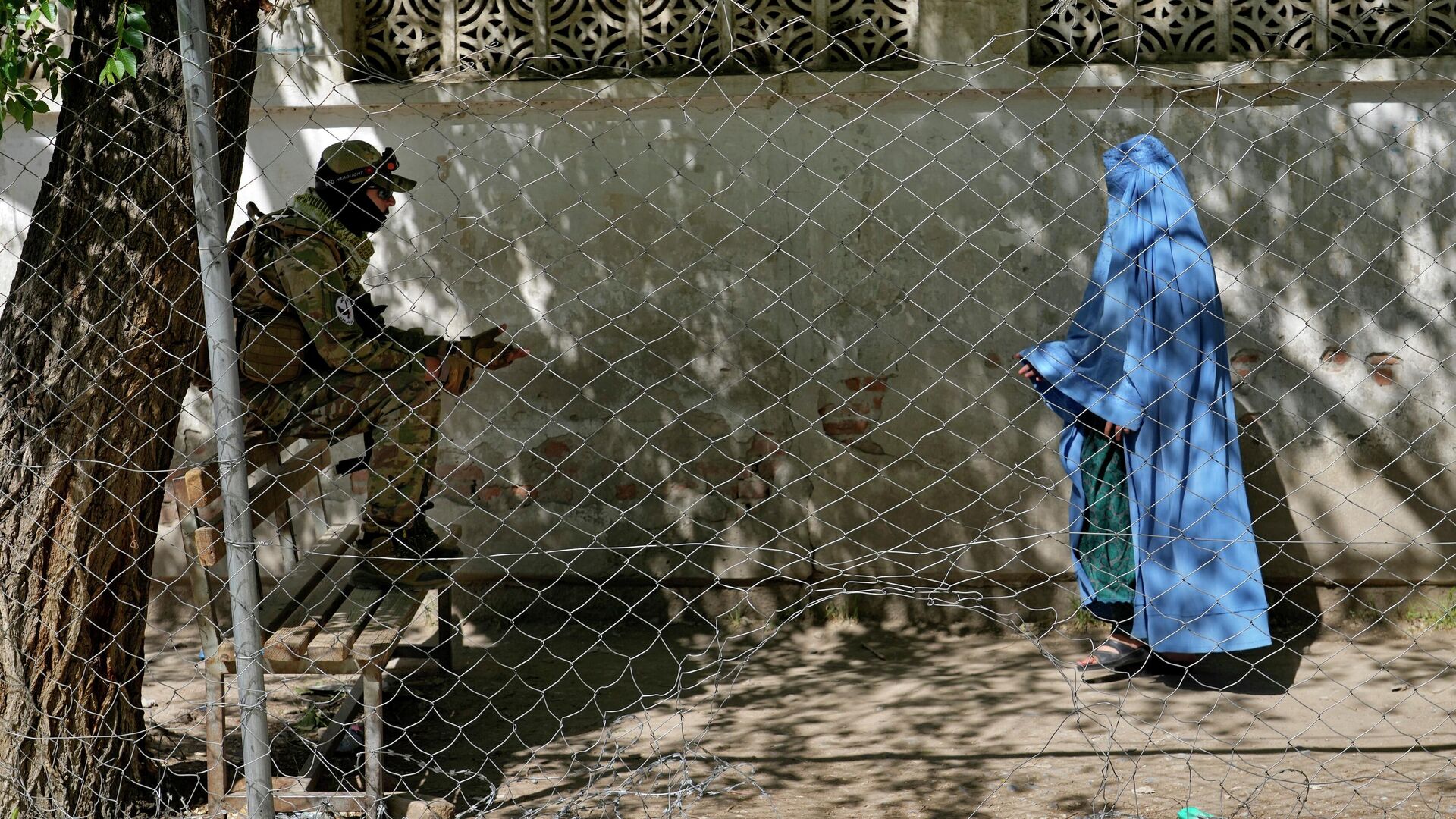 A Taliban fighter stands guard as a woman enters the government passport office in Kabul, Afghanistan, Wednesday, April 27, 2022. Afghanistan's Taliban leadership has ordered all Afghan women to wear the all-covering burqa in public.  - Sputnik India, 1920, 10.01.2023