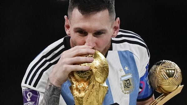 Argentina's Lionel Messi kisses the World Cup trophy with the golden ball trophy in his hand after the World Cup final soccer match between Argentina and France at the Lusail Stadium in Lusail, Qatar, Sunday, Dec. 18, 2022. - Sputnik India