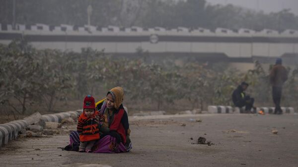 A migrant worker holds her baby as she waits to be hired for work on a foggy morning in New Delhi, India, Tuesday, Dec. 20, 2022. - Sputnik भारत