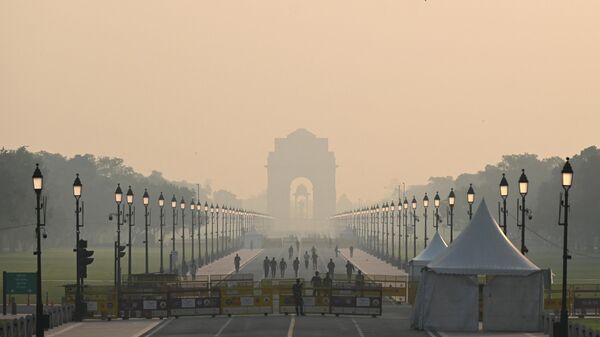 People walk along a road near India Gate amid smoggy conditions in New Delhi on October 25, 2022. - Sputnik India