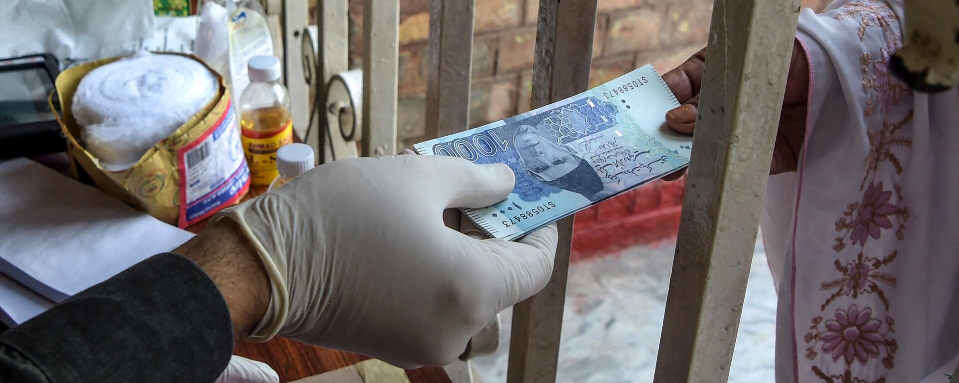 A woman (R) gets rupee notes as she collects cash of financial assistance through a district administration counter under the governmental Ehsaas Emergency Cash Programme for families in need during a government-imposed nationwide lockdown as a preventive measure against the COVID-19 coronavirus, in Peshawar on April 9, 2020 - Sputnik India, 1920, 10.01.2023