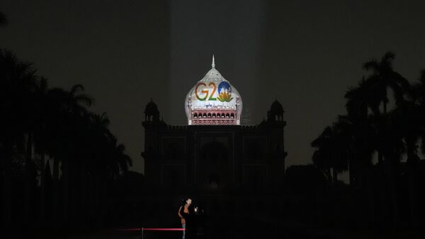 A television correspondent reports standing in front of Safdarjung's tomb lit up with the G20 logo, in New Delhi, Thursday, Dec. 1, 2022. - Sputnik भारत