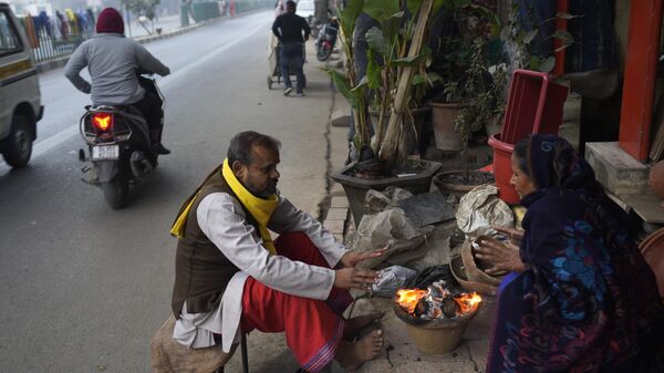 People warm themselves around a bonfire as temperatures plummet in New Delhi, India, Tuesday, Dec. 27, 2022. - Sputnik India