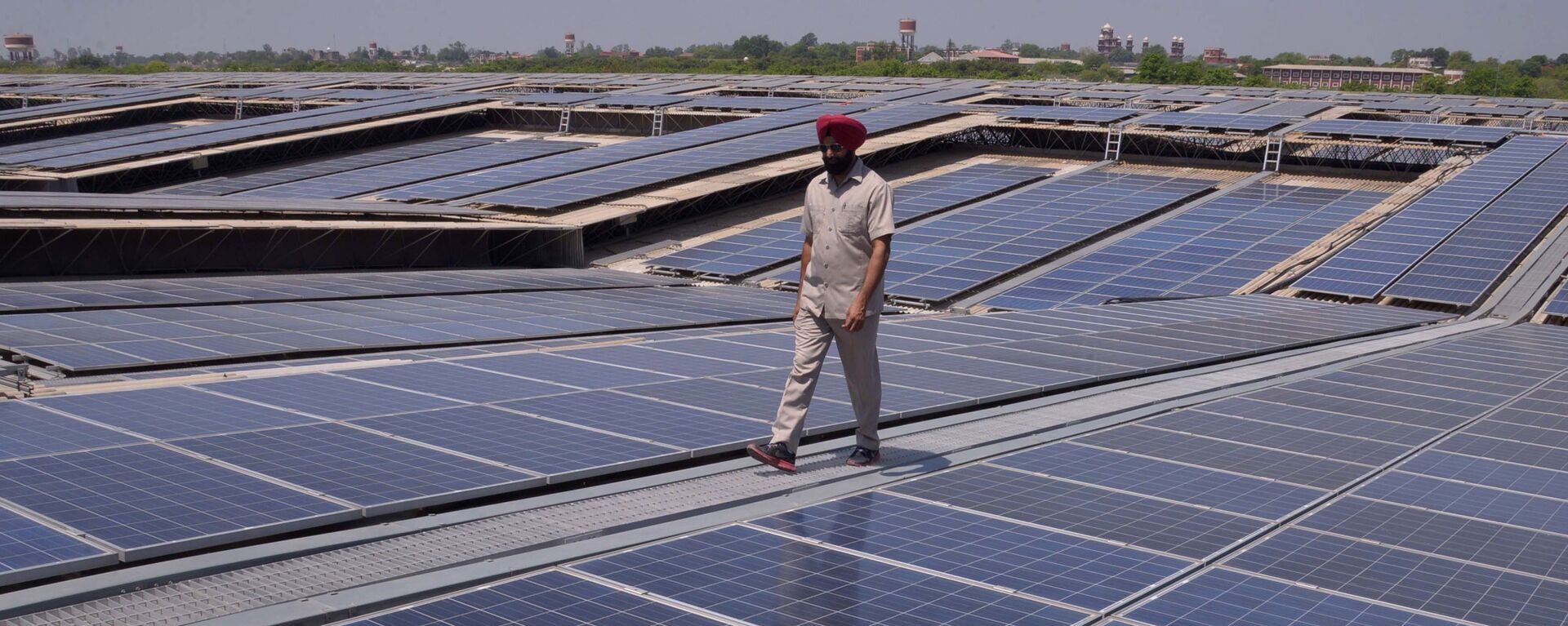 An Indian security personnel poses for media as he walks over rooftops covered in solar panels at the Solar Photovoltaic Power Plant, some 45kms from Amritsar. (File) - Sputnik India, 1920, 04.01.2023