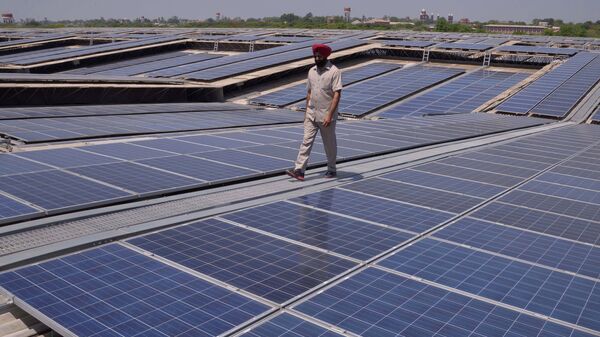 An Indian security personnel poses for media as he walks over rooftops covered in solar panels at the Solar Photovoltaic Power Plant, some 45kms from Amritsar. (File) - Sputnik India