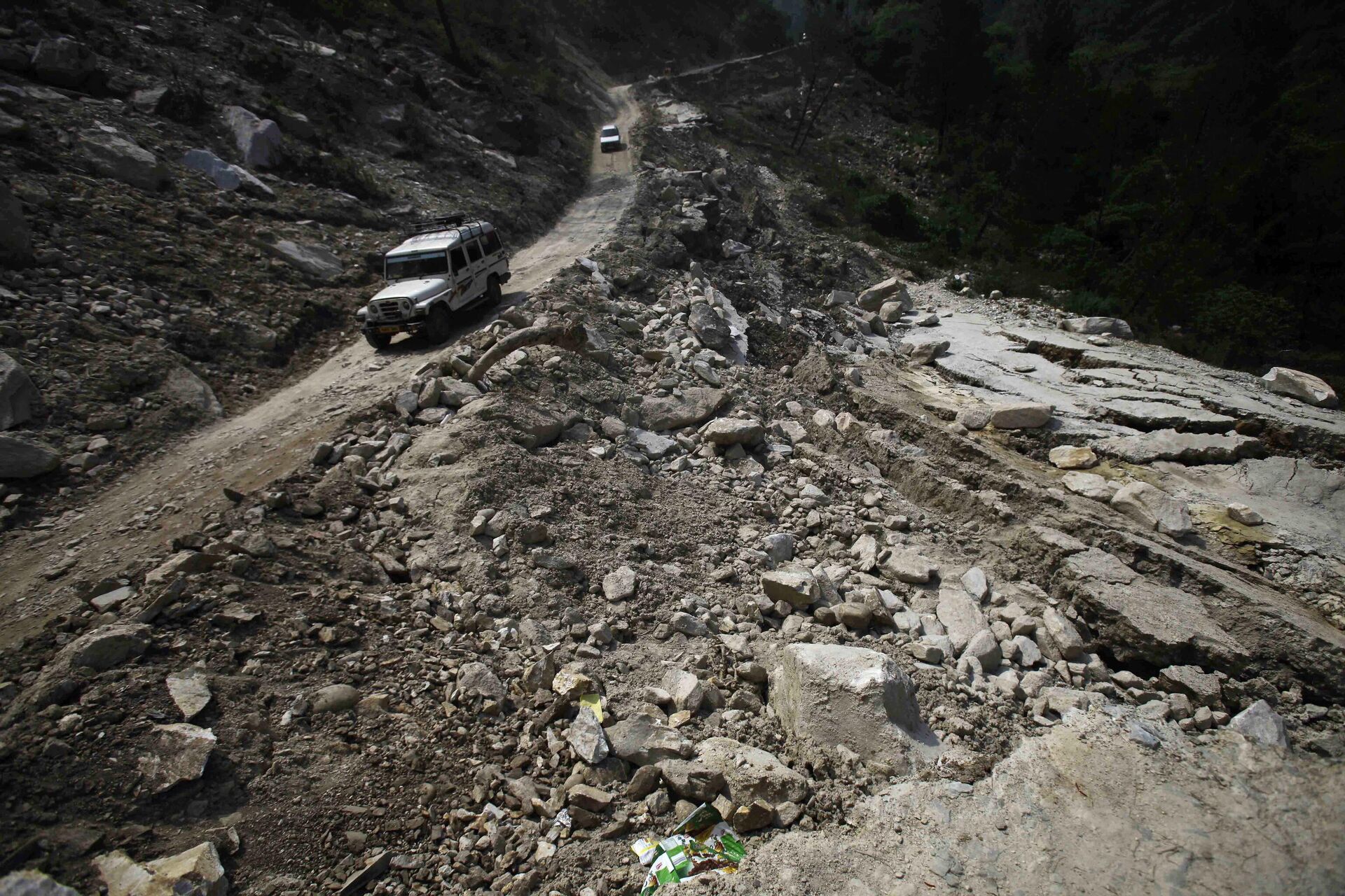  Cars are seen on a road destroyed by landslides and floods,  in Joshimath, India, Friday, June 21, 2013. The heavy rains caused by the annual monsoon have left more than 500 people dead and stranded tens of thousands, mostly pilgrims, in India’s northern mountainous region, officials said Friday.  - Sputnik India, 1920, 25.09.2023
