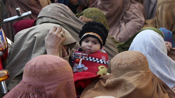 People stand in a long queue and wait to buy subsidized sacks of wheat flour in Peshawar, Pakistan, Monday, Jan. 9, 2023. - Sputnik India