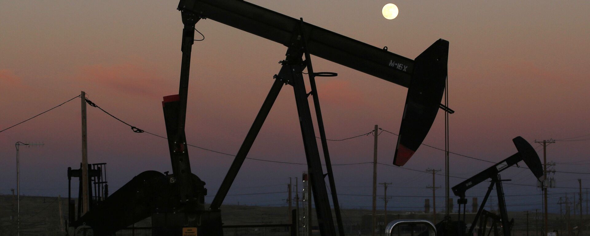 FILE - In this June 8, 2017, file photo, oil derricks are busy pumping as the moon rises near the La Paloma Generating Station in McKittrick, Calif. The U.S. is on pace to leapfrog both Saudi Arabia and Russia as the world’s biggest oil producer - Sputnik India, 1920, 04.04.2024