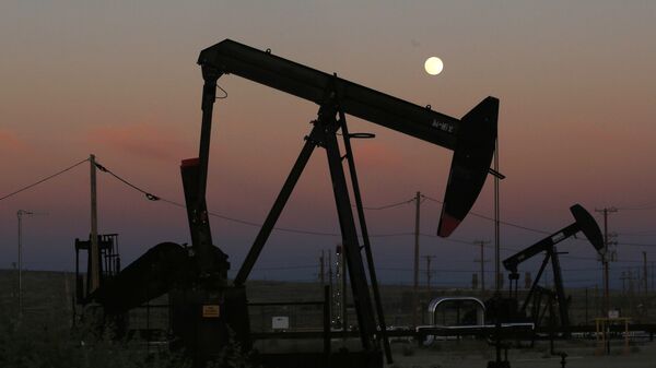 FILE - In this June 8, 2017, file photo, oil derricks are busy pumping as the moon rises near the La Paloma Generating Station in McKittrick, Calif. The U.S. is on pace to leapfrog both Saudi Arabia and Russia as the world’s biggest oil producer - Sputnik भारत