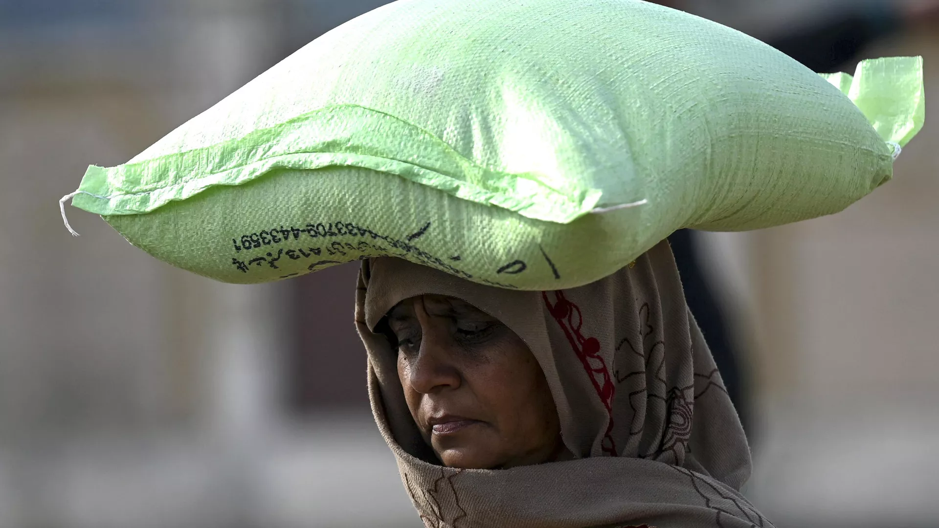 A woman carries a sack of wheat flour after purchasing at government-controlled prices in Islamabad on January 10, 2023.