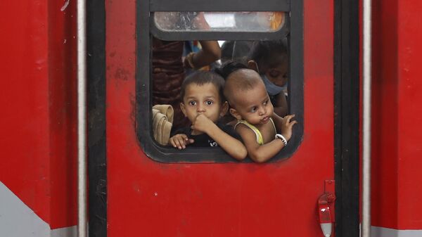 In this Saturday, May 30, 2020 photo, Indian migrant worker's children peer out from the window of their train in Prayagraj, India, as they return to villages - Sputnik भारत
