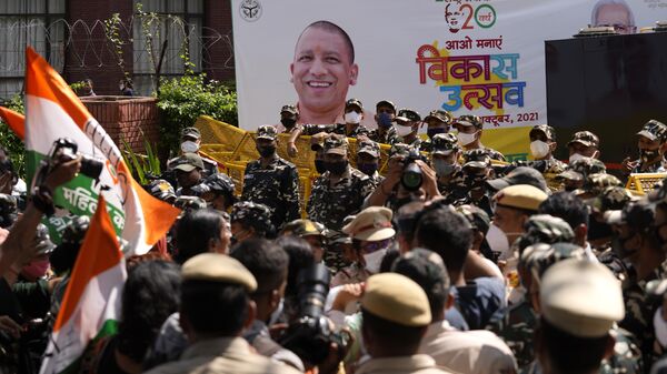 A banner of development festival displays a photograph of Uttar Pradesh Chief Minister Yogi Adityanath as paramilitary force soldiers detain activists of Congress party's youth wing protesting against Sunday's killing of four farmers in Uttar Pradesh state after being run over by a car owned by India's junior home minister in New Delhi, India, Monday, Oct. 4, 2021. - Sputnik India