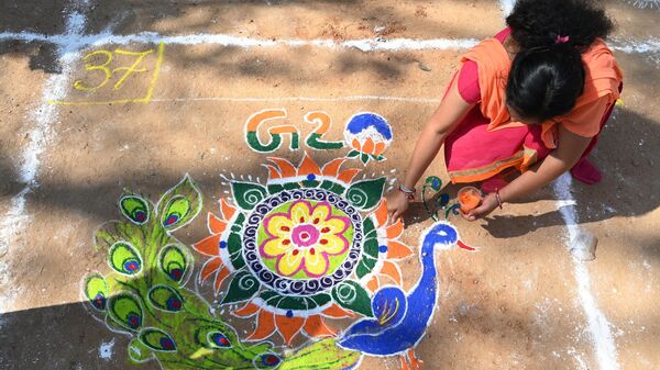 A woman applies coloured powder to a rangoli design with G-20 theme during a rangoli competition ahead of the Sankranthi festival in Hyderabad on January 11, 2023. - Sputnik India