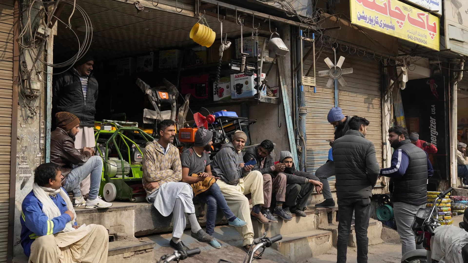 Shopkeepers and workers wait for electric power at a market following a power breakdown across the country, in Lahore, Pakistan, Monday, Jan. 23, 2023.