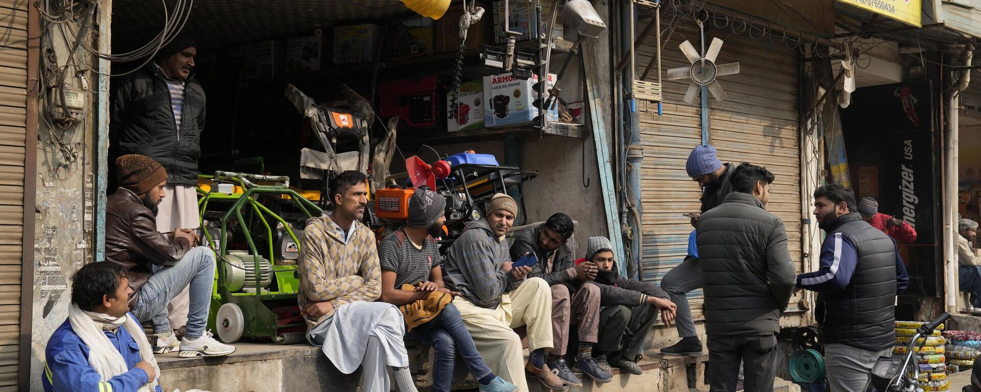 Shopkeepers and workers wait for electric power at a market following a power breakdown across the country, in Lahore, Pakistan, Monday, Jan. 23, 2023. - Sputnik India, 1920, 23.01.2023