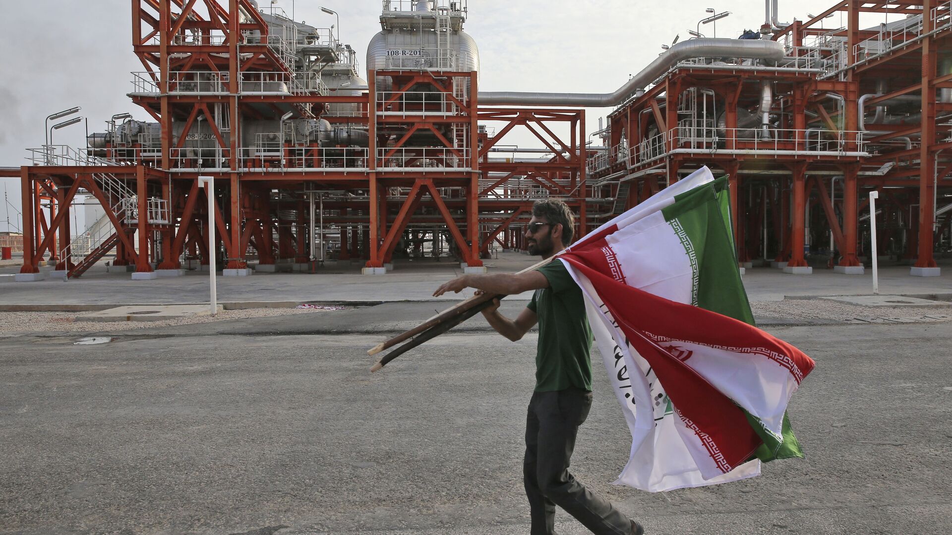 An Iranian worker carries Iranian flags prior to an inauguration ceremony of a natural gas refinery at the South Pars gas field on the northern coast of the Persian Gulf, in Asaluyeh, Iran - Sputnik India, 1920, 01.02.2023
