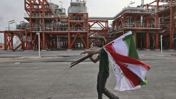 An Iranian worker carries Iranian flags prior to an inauguration ceremony of a natural gas refinery at the South Pars gas field on the northern coast of the Persian Gulf, in Asaluyeh, Iran - Sputnik India