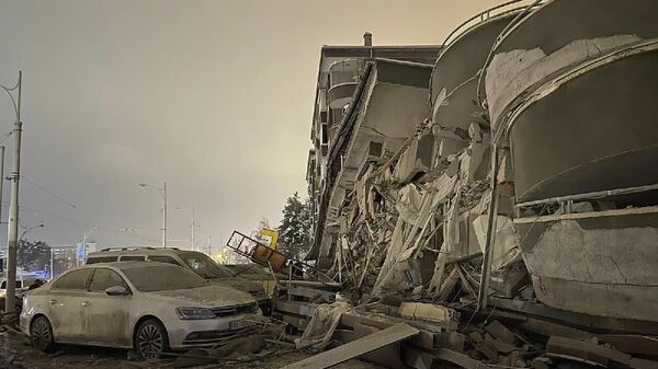 Damaged vehicles sit parked in front of a collapsed building following an earthquake in Diyarbakir, southeastern Turkey, early Monday, Feb. 6, 2023. - Sputnik भारत