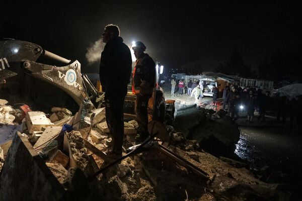 Syrian rescuers (White Helmets) and residents gather near a collapsed building  follwoing an earthquake, in the border town of Azaz in the rebel-held north of the Aleppo province, early on February 6, 2023 - Sputnik भारत