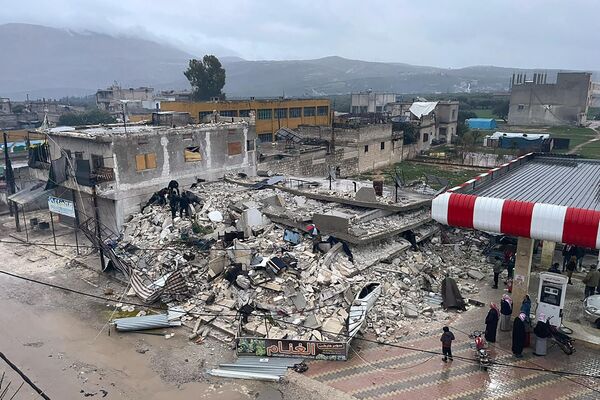 People search through the wreckage of a collapsed building in Azmarin town, in Idlib province, northern Syria, Monday, Feb. 6, 2023. - Sputnik भारत