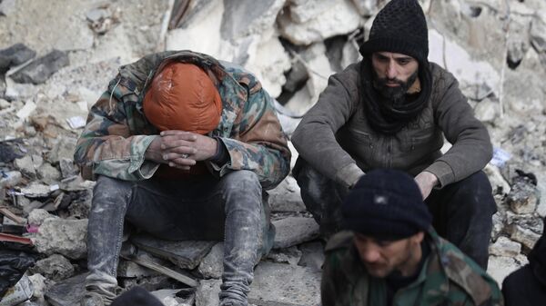 People react as they sit on the wreckage of collapsed buildings, in Aleppo, Syria, Tuesday, Feb. 7, 2023. - Sputnik India