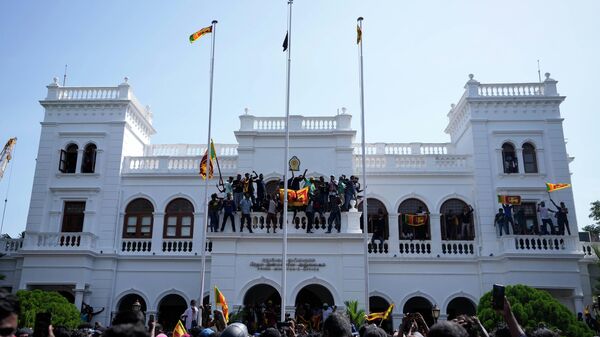 Sri Lankan protesters, some carrying national flags, stand on top of prime minister Ranil Wickremesinghe 's office, demanding he resign after president Gotabaya Rajapaksa fled the country amid economic crisis in Colombo, Sri Lanka, Wednesday, July 13, 2022. - Sputnik India