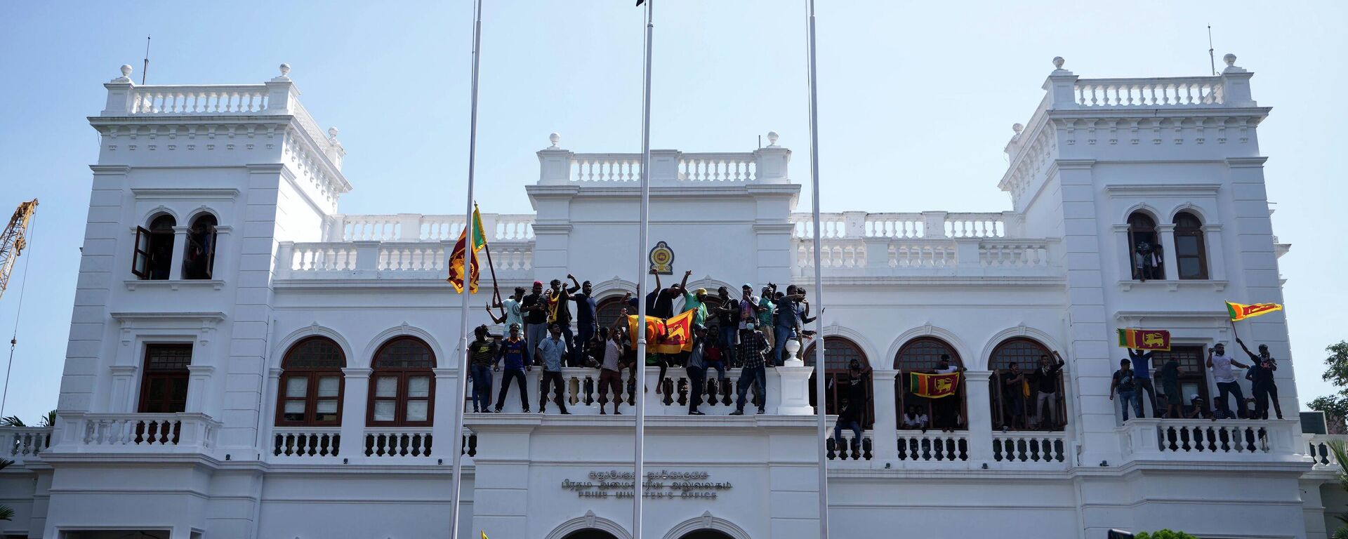 Sri Lankan protesters, some carrying national flags, stand on top of prime minister Ranil Wickremesinghe 's office, demanding he resign after president Gotabaya Rajapaksa fled the country amid economic crisis in Colombo, Sri Lanka, Wednesday, July 13, 2022. - Sputnik India, 1920, 08.07.2023
