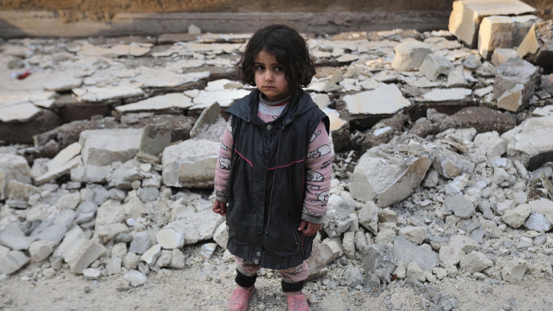A Syrian girl stands amidst debris from a collapsed building on February 7, 2023, in the town of Jandairis, as search and rescue operations continue following a deadly earthquake. - Sputnik India, 1920, 09.02.2023