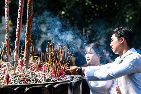 A couple burns incense during a collective wedding ceremony in downtown Hanoi on October 15, 2022. - Sputnik India