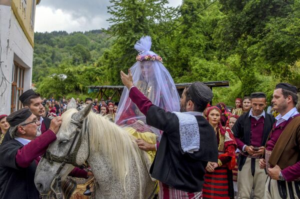 A bride, wearing a veil, rides a horse heading to the chuch during the traditional Galicnik Wedding ceremony in the Macedonia's western village of Galicnik, on July 18, 2021. - Sputnik India