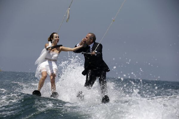 Lebanese groom Tommy kisses the hand of his bride Nadine's while water skiing dressed in their wedding clothes in the waters off the bay of Jounieh, north of Beirut, on May 29, 2017. - Sputnik India