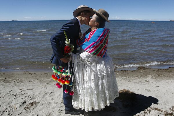 Ecuadorian Bryan Rosel and his wife Magdalena Llanque -who met more than a year ago through social media- kiss after getting married during a mass wedding ceremony where fifty couples got married at the shore of lake Titicaca in the Aymara district of Acora in Puno, Peru, on August 20, 2022. - Sputnik India