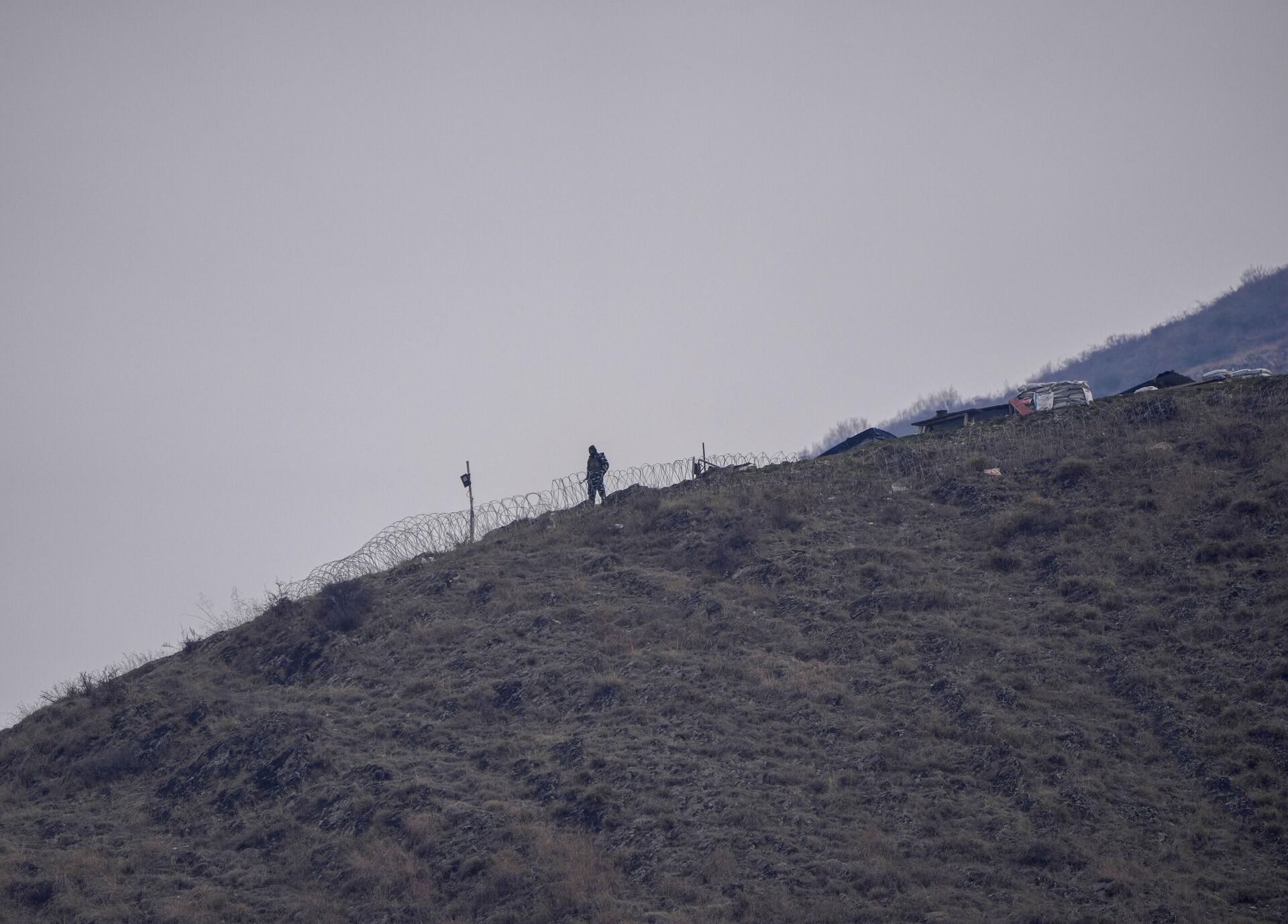 An Indian paramilitary soldiers guards on a nearby mountain as others attend a memorial dedicated to soldiers who were killed in a 2019 attack at the Central Reserve Police Force headquarters in Lethpora, Indian-controlled Kashmir, Monday, Feb. 14, 2022. - Sputnik India, 1920, 02.04.2024