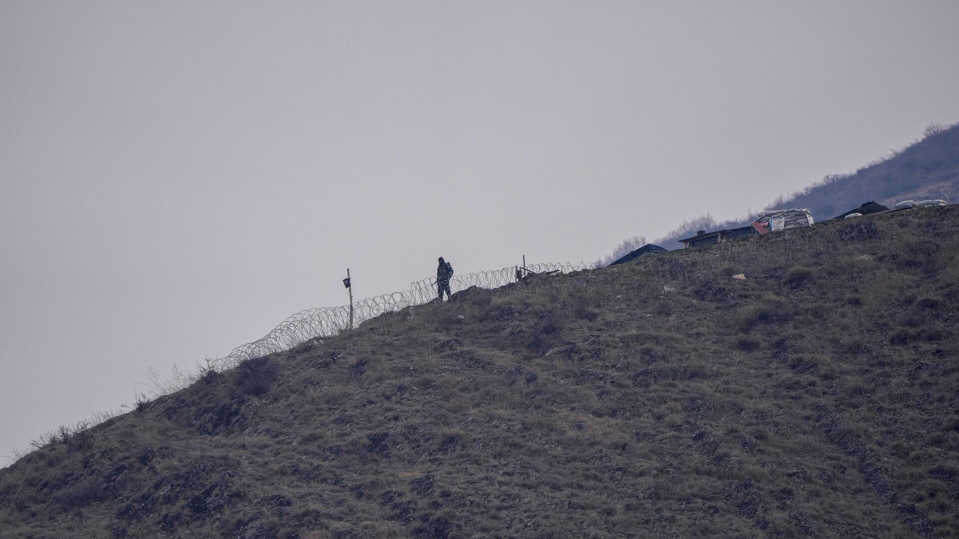 Indian paramilitary soldiers guard a nearby mountain as others attend a memorial dedicated to soldiers who were killed in a 2019 attack at the Central Reserve Police Force headquarters in Lethpora, Indian-controlled Kashmir, Monday, 14 February 2022. - Sputnik India, 1920, 14.02.2023