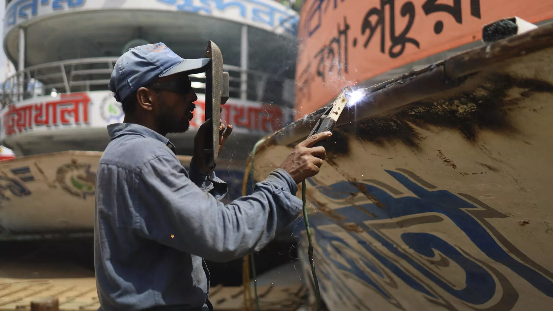 A worker welds the hull of a ferry boat in Dhaka on June 22, 2022.