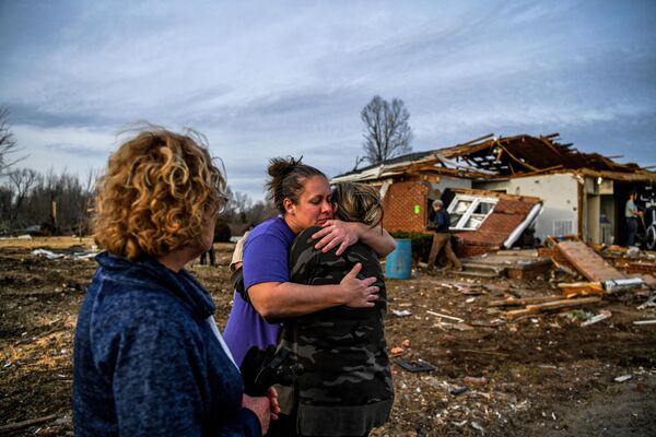 Ginny Watts (C) hugs her friend as they help cleaning her destroyed home in Dawson Springs, Kentucky, on December 14, 2021, four days after tornadoes hit the area. - It is normally a joyous season, but in tornado-blasted Kentucky thousands of families are in crisis days before Christmas, including 13-year-old Andrew Humphrey's, recently made homeless by the worst storm in state history.
 - Sputnik India