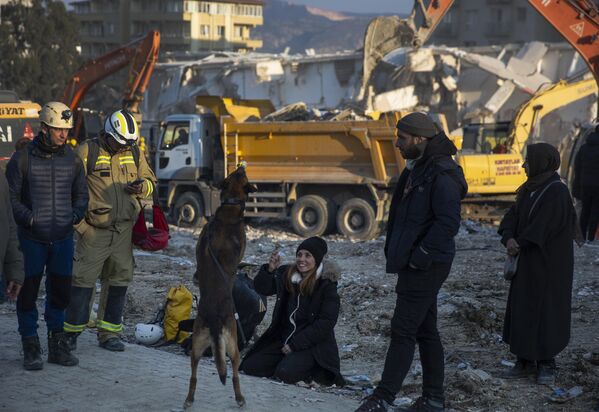 A woman plays with a sniffer dog as rRescue workers continue the search for victims of the earthquake in Antakya, Turkey, Saturday, Feb. 11, 2023. - Sputnik India