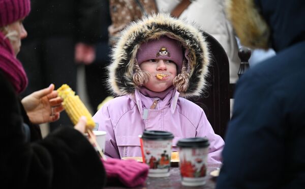मास्को में मासलेनित्सा को मनाने के दौरान लड़की पेनकेक्स खा रही है।  - Sputnik भारत