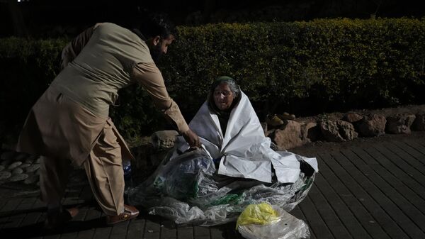 An Afghan youth gives alms to a beggar woman in Daman-e-Koh park, north of Islamabad, Pakistan, Thursday, Feb. 9, 2023. - Sputnik India