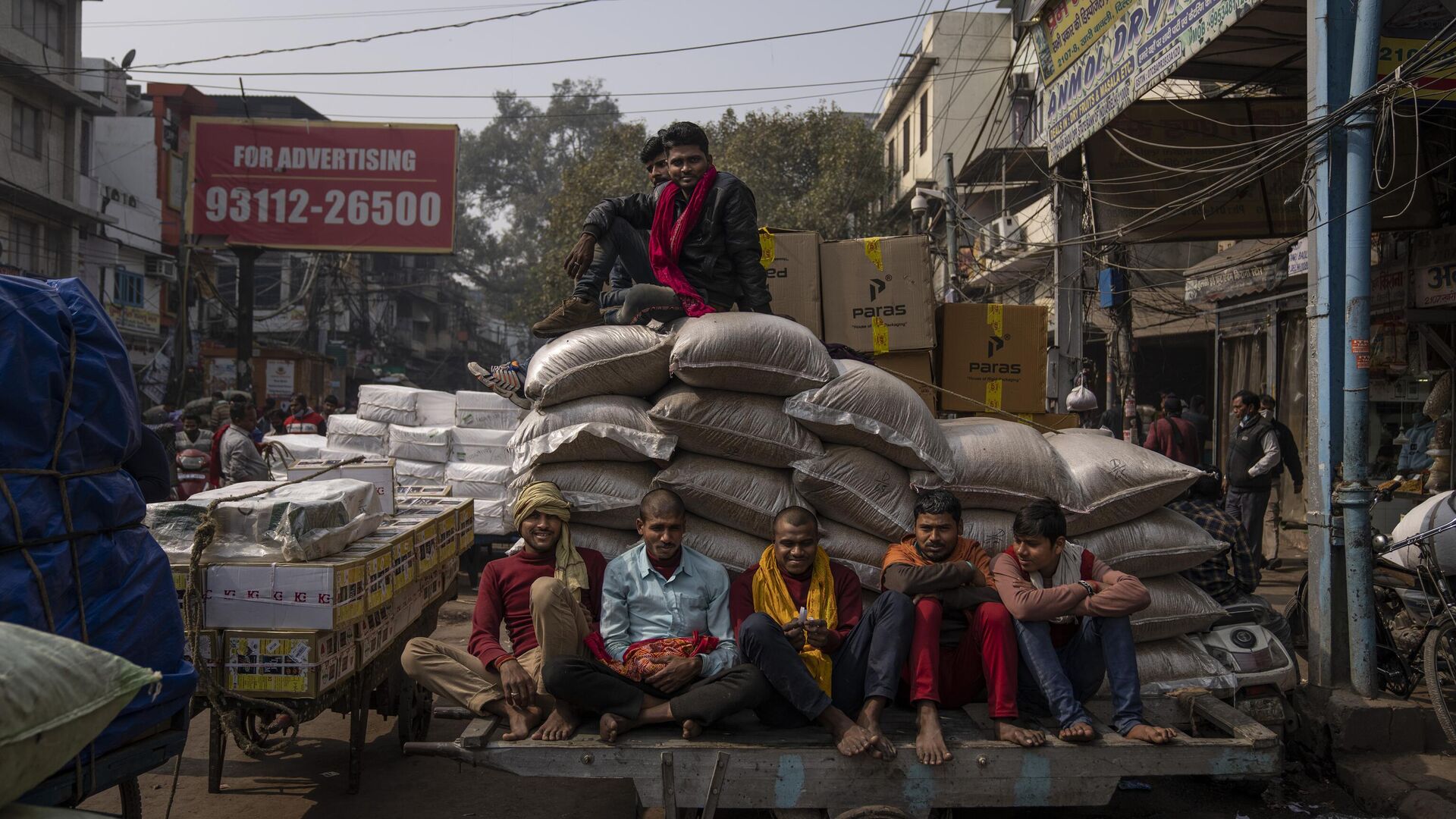 Indian laborers sit on a handcart as others sit atop goods ready for transportation at a wholesale market in New Delhi, India, Tuesday, Feb. 1, 2022. - Sputnik India, 1920, 22.02.2023