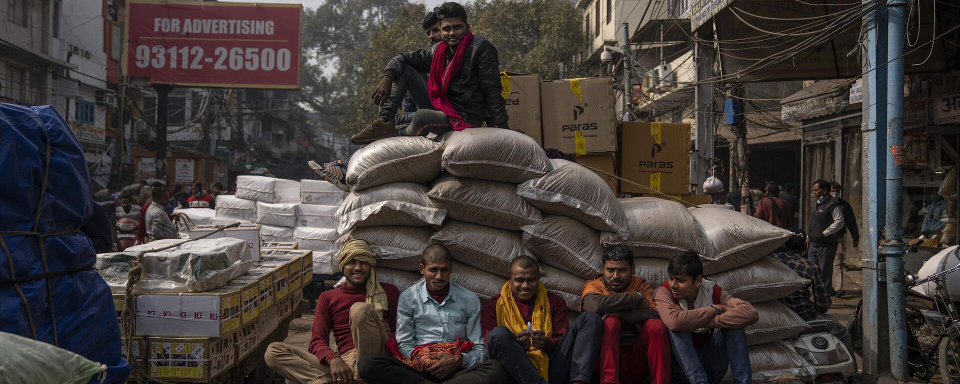 Indian laborers sit on a handcart as others sit atop goods ready for transportation at a wholesale market in New Delhi, India, Tuesday, Feb. 1, 2022. - Sputnik India, 1920, 04.04.2023