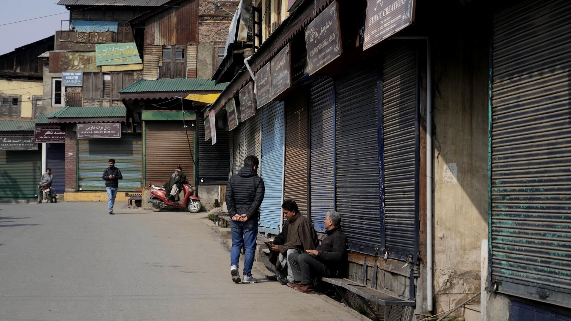 People sit outside closed shops as they spend time in Srinagar, Wednesday, Feb. 15, 2023. - Sputnik India, 1920, 22.02.2023
